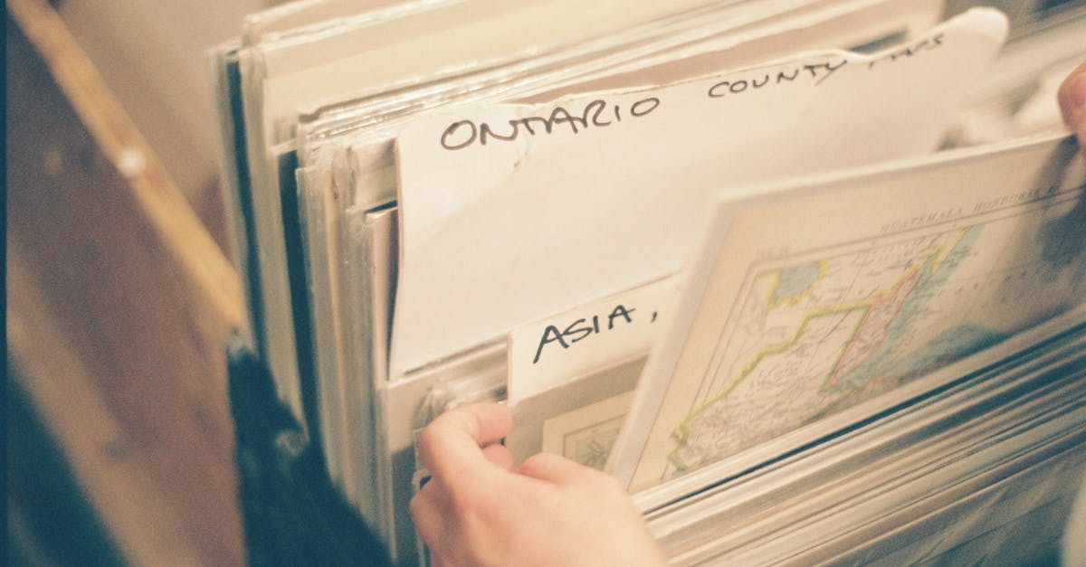 Can't see a map or select pokémon - From above of anonymous person selecting paper maps with captions in stack while spending time in library with blurred background