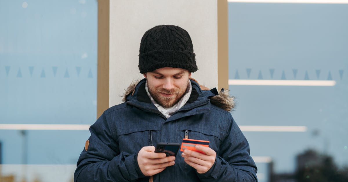 Can't talk to merchant to buy Gwent card? - Cheerful man entering details of credit card on smartphone on street Can't talk to merchant to buy Gwent card? - Cheerful man entering details of credit card on smartphone on street
