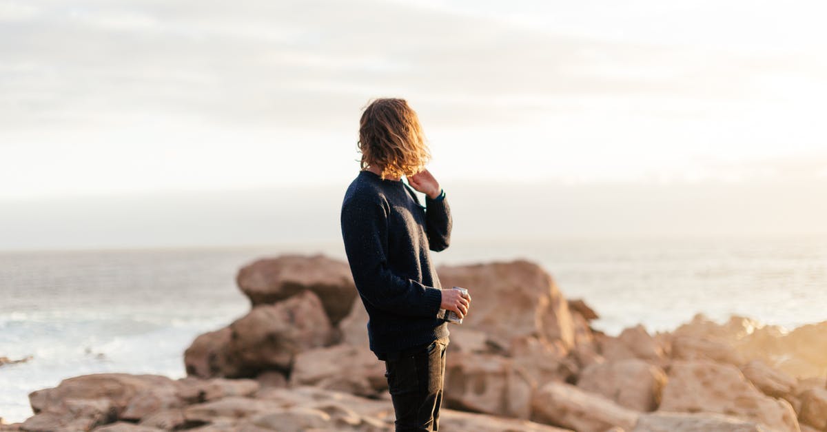 Can a 'blank space' ability be replaced? - Side view of anonymous male traveler with can of beverage admiring ocean from rough rocks under shiny sky in evening