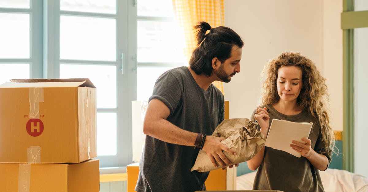 Can a fun pack unlock the level? - Cheerful young man and woman smiling while unpacking carton boxes with belongings in new apartment during relocation and looking at paper Can a fun pack unlock the level? - Cheerful young man and woman smiling while unpacking carton boxes with belongings in new apartment during relocation and looking at paper