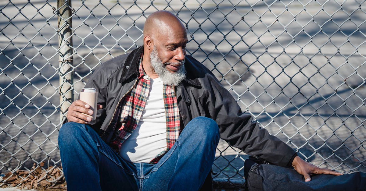 Can a silk touch pickaxe be used in a quarry? - Hairless aged ethnic male in casual outfit touching bag while sitting against mesh fence with beer can