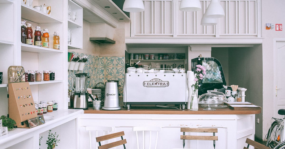 Can a tool cupboard be moved? - White kitchen set with coffee maker and appliances in small cozy coffee shop with flowers and table in daylight