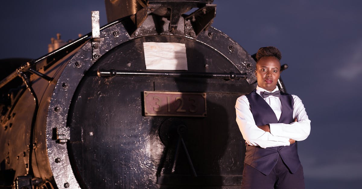 Can a train cross this junction? - Boy in White Dress Shirt and Black Pants Standing on Black Metal Wheel