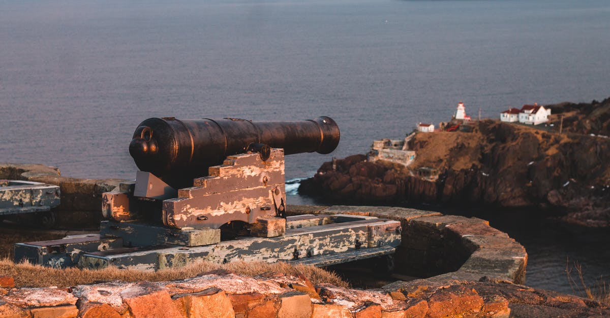 Can I aim the cannons in chalice dungeons - Blue sky over rocky shore of big endless bay and long black old cannon surrounded by brick curb