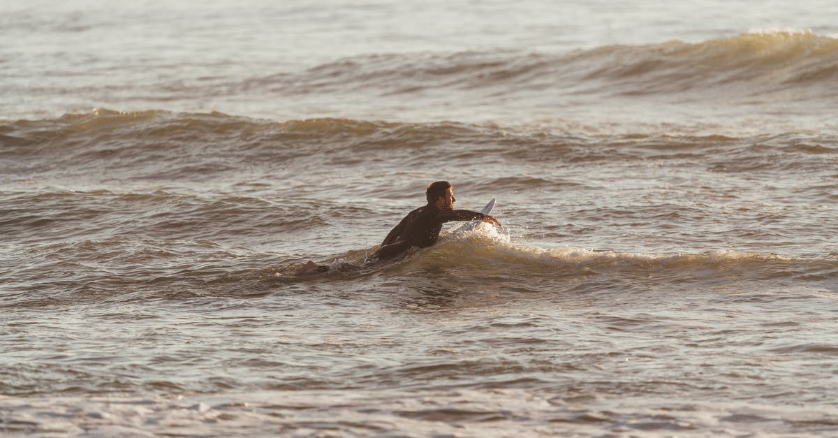 Can I catch Pokémon when I move very quickly? - Side view of sporty male with surfboard catching wave in rippling water of ocean