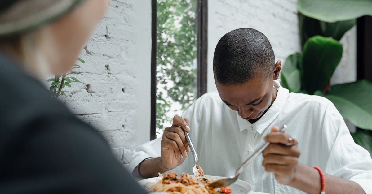Can I drop arrows down after hitting a mob? - Young black woman looking down at white shirt stained with food while having pasta in cafe together with unrecognizable friend