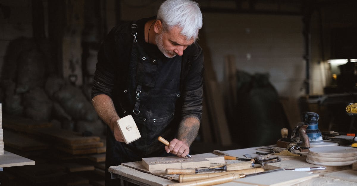 Can I duplicate magazines other than S.P.E.C.I.A.L. to gain skills? - Serious male woodworker in apron using mallet and chisel to carve wooden board at table with abundance of instruments in carpentry