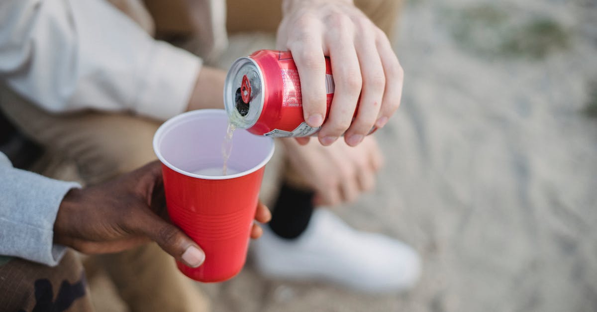 Can I farm Chlorophyte above ground level? - From above of crop anonymous man pouring fizzy drink from can into red plastic cup of black friend while sitting on sandy ground