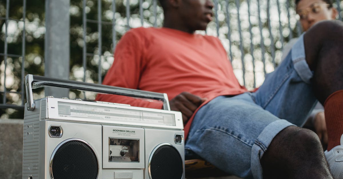 Can I free the radio spokesperson in Just cause 3? - From below of crop young African American male friends listening to music on retro cassette recorder with radio while sitting near metal grid of park Can I free the radio spokesperson in Just cause 3? - From below of crop young African American male friends listening to music on retro cassette recorder with radio while sitting near metal grid of park