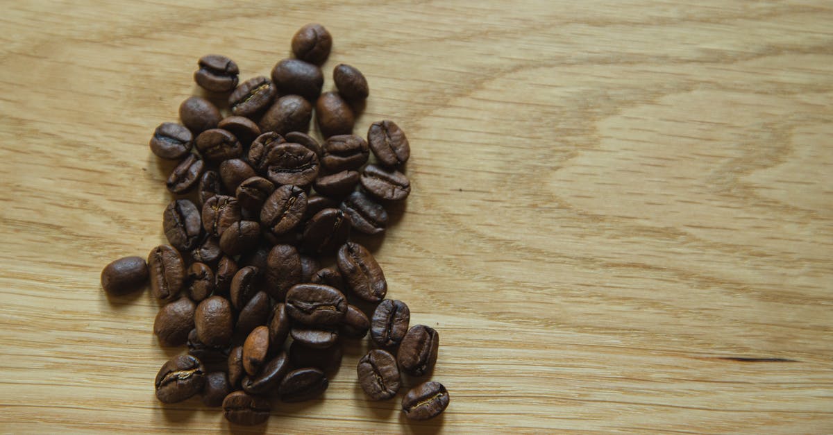 Can I make my world a seed? - Top view of scattered coffee beans placed on wooden table before making coffee