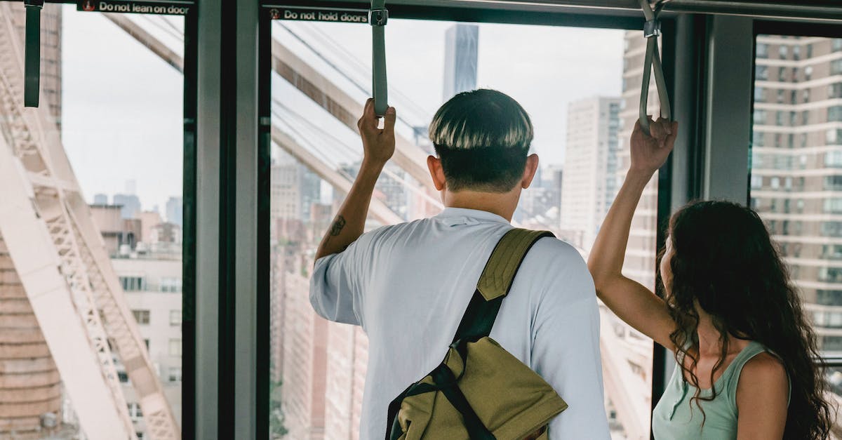 Can I move my downloaded Origin games to another location without reinstalling them? - Back view faceless couple in casual clothes riding funicular cabin and grabbing hangers while looking away on urban city views