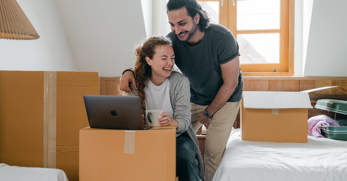 Can I move my new leaf save file to my computer? - Happy diverse couple with laptop sitting in attic style bedroom