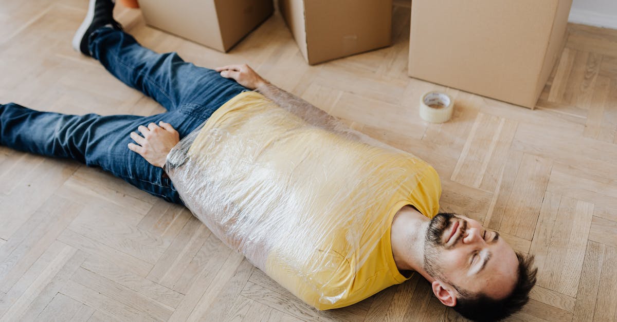 Can I move my save data/will it be automatically moved from Sleeping Dogs to SD: Definitive Edition? - High angle of tired male in casual wear wrapped in plastic tape and lying on parquet with eyes closed near carton boxes during relocation