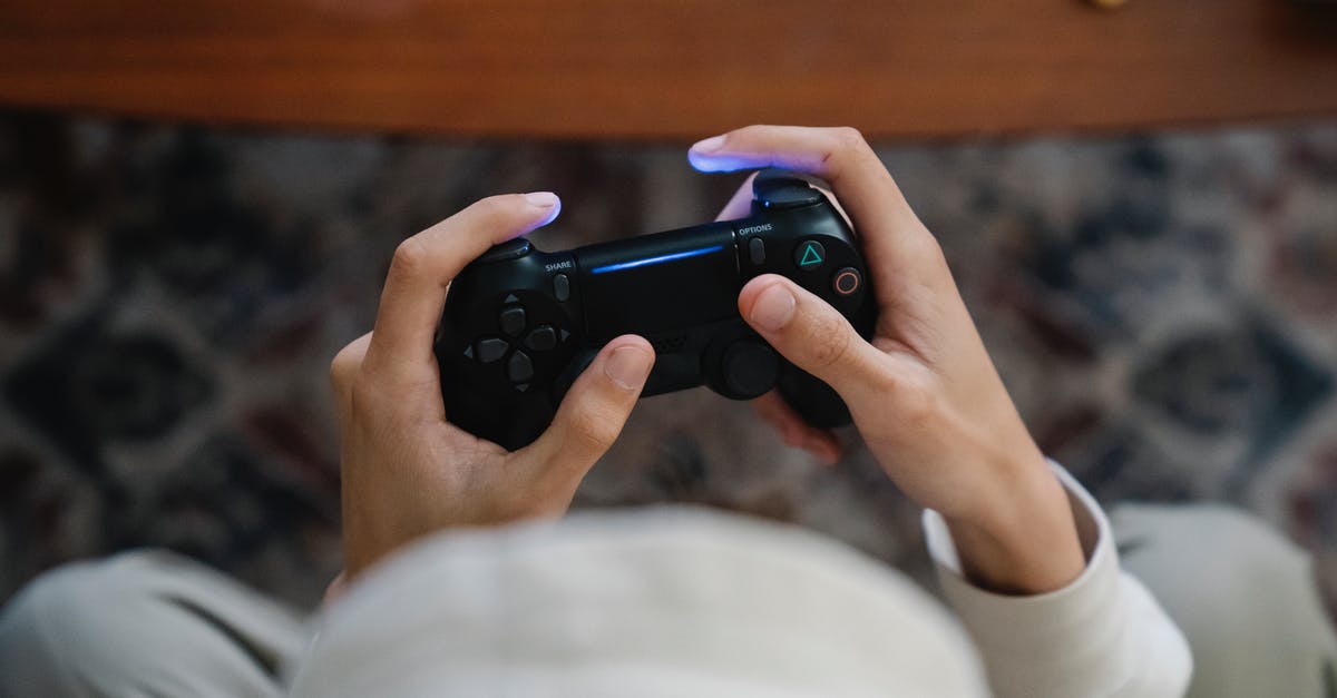 Can I play multiplayer on two consoles with game from the same account? - From above of crop unrecognizable male with console controller playing video game in living room