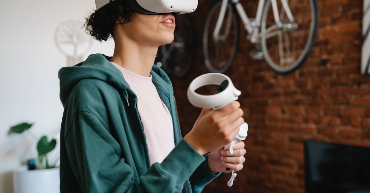 Can I play Sims 4 on my Mac using a PS3 controller? - Crop male gamer wearing VR goggles standing with controllers and playing video game in cyberspace