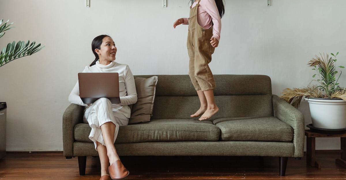 Can I rocket jump with a controller on pc? - Smiling Asian mother in casual wear working on laptop while cute daughter jumping on couch in cozy living room Can I rocket jump with a controller on pc? - Smiling Asian mother in casual wear working on laptop while cute daughter jumping on couch in cozy living room