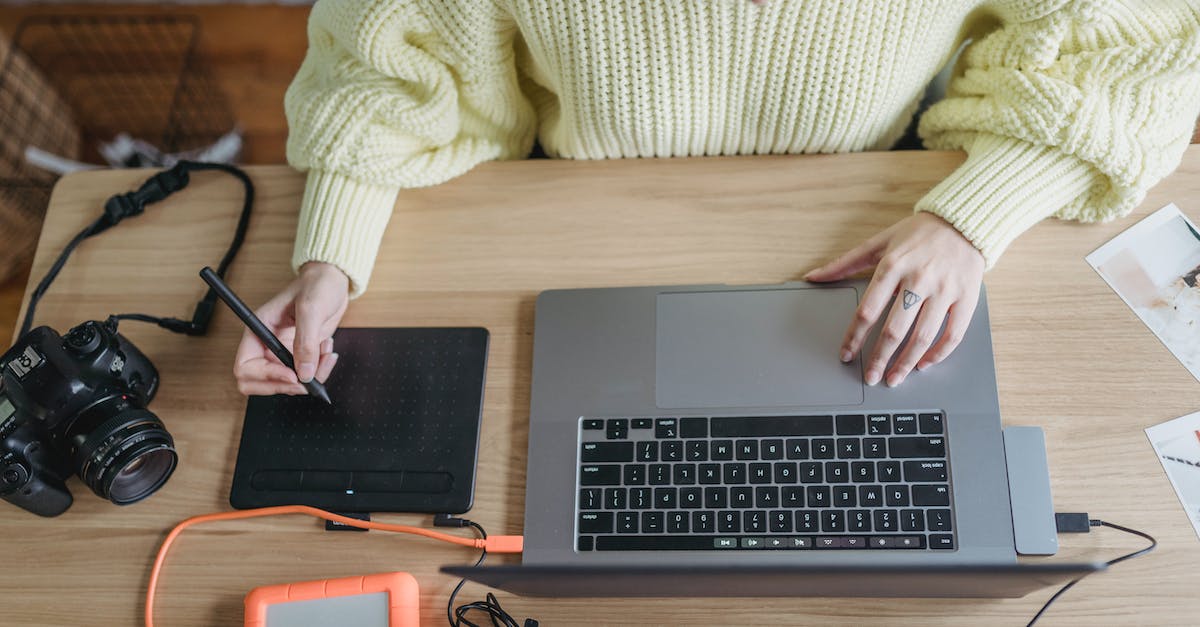 Can I run games from an external hard drive? [closed] - From above of crop faceless female photographer using graphic tablet while editing photos on netbook at table with photo camera