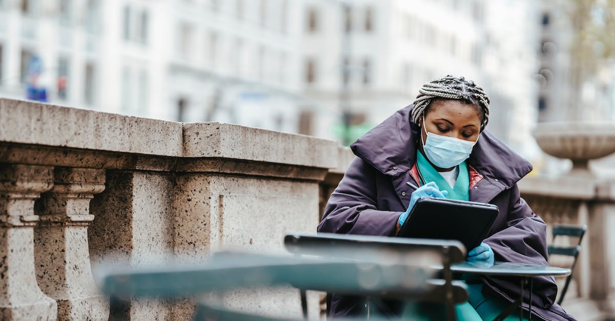 Can I siege/take county that is under the control of a revolt? - Focused African American woman in protective mask and gloves sitting at table and writing information in balcony
