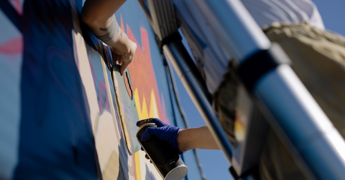 Can I swap round a built wall in Rust from soft side to hard side? - From below of crop unrecognizable person in casual clothes and gloves using spray can while painting graffiti wall standing on ladder