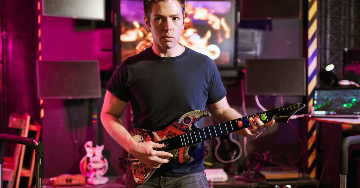 Can I sync a Guitar Hero World Tour controller dongle with a Guitar Hero 3 guitar? - Man Holding Guitar Controller Can I sync a Guitar Hero World Tour controller dongle with a Guitar Hero 3 guitar? - Man Holding Guitar Controller