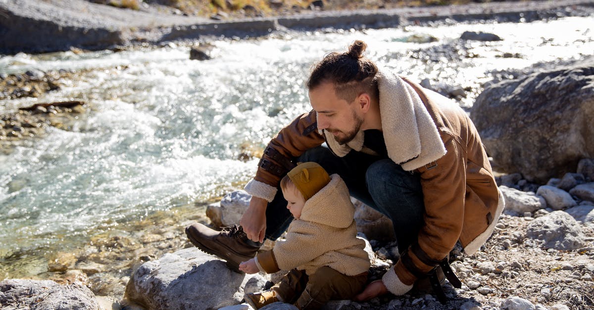 Can I time travel to the next time a villager asks to move out or do I have to play the whole 15 days - Bearded young father with little child in casual warm clothes sitting on rocky ground near river and enjoying time together while weekend