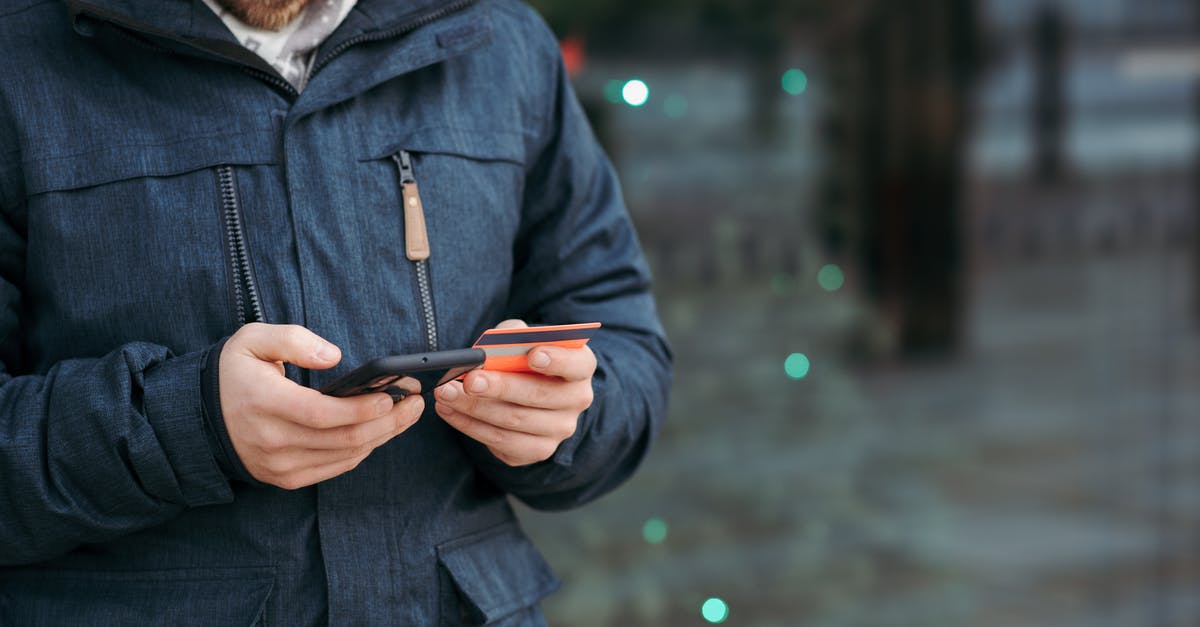 Can I transfer money to another player on GTA V online? - Man browsing smartphone and holding credit card on street