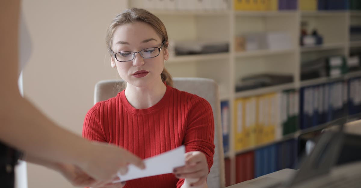 Can I upgrade my child's account to an adult account? - Serious young female employee in casual clothes and eyeglasses reading attentively document while working in office with colleague