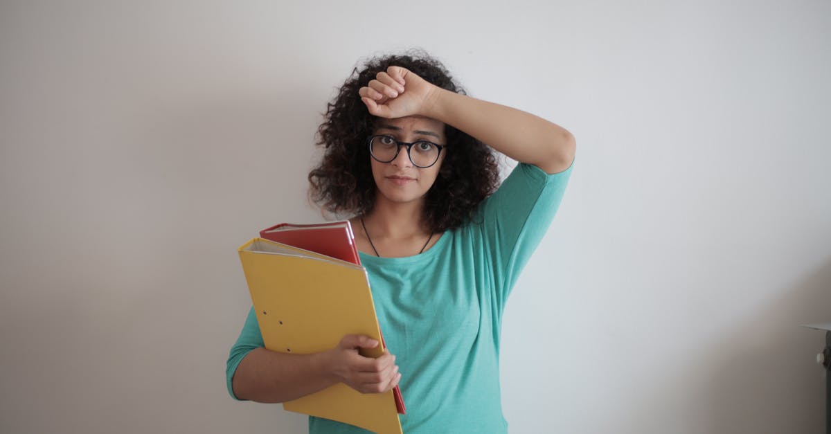 Can I upgrade my child's account to an adult account? - Unhappy overworked female employee in glasses and casual clothes with folders of documents looking at camera with sadness and touching head while standing against white wall in contemporary office