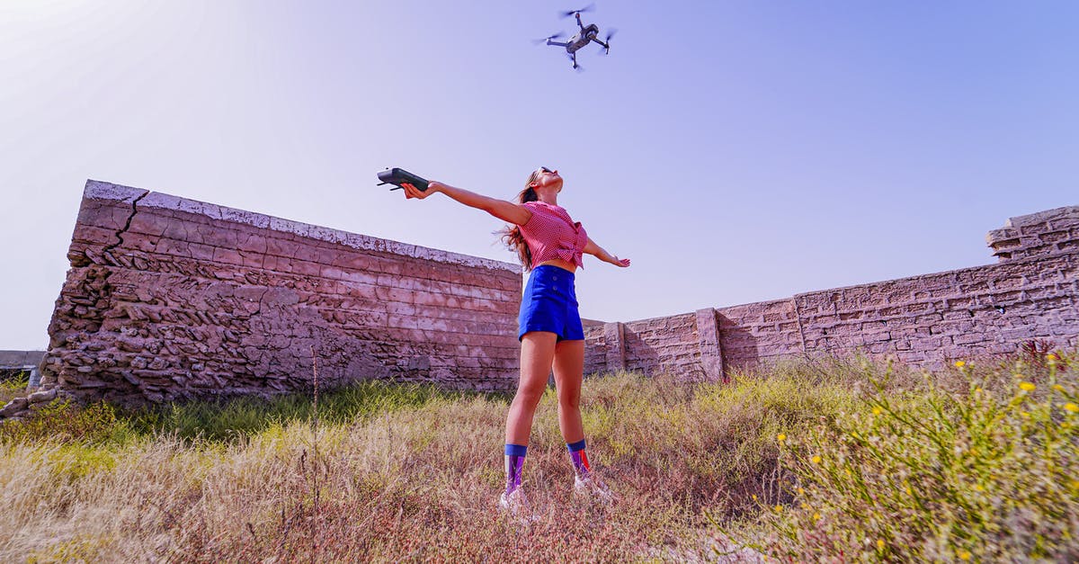 Can I use my PS3 remote control on my PS4 - Fit woman standing with arms outstretched under flying drone