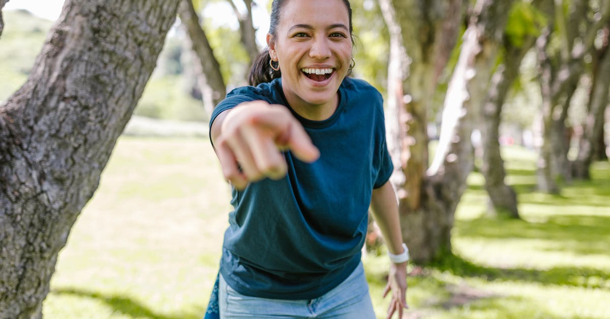 Can I win a culture victory after I win a science victory? - Smiling Woman in Green Crew Neck T-shirt and Blue Denim Jeans Standing Beside Brown Tree
