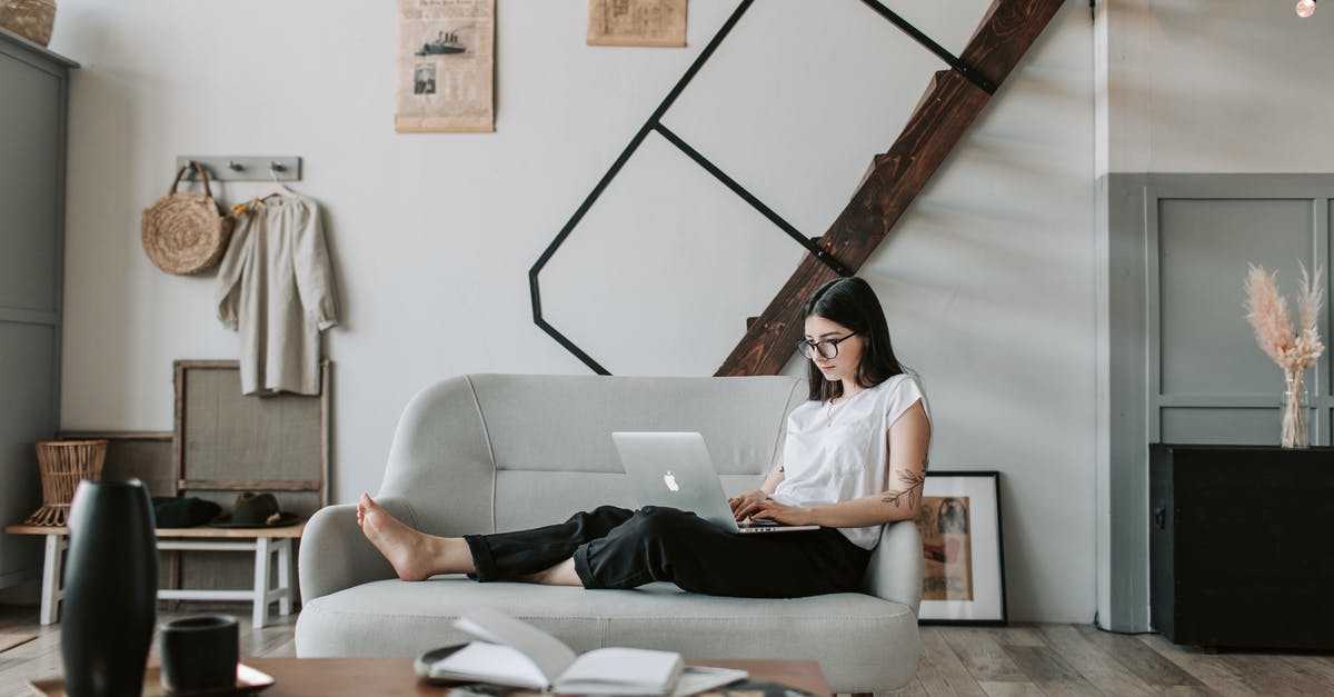Can mobs break down wooden doors? [duplicate] - Positive female with tattooed arms wearing casual clothes and eyeglasses reading netbook while sitting barefoot on comfortable sofa behind table with books and magazines in modern apartment with minimalist interior in eco style during free time