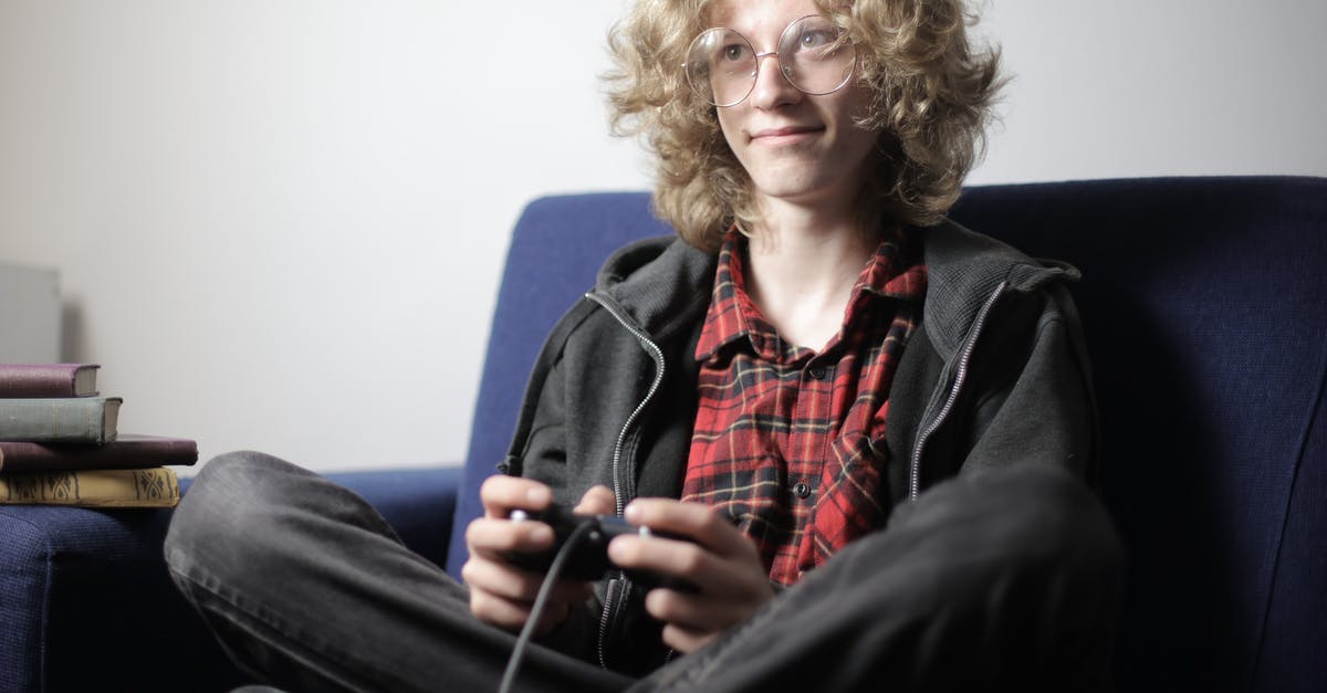 Can one HDD be connected to more than one PS3 console to play games at the same time? - Smiling teenager playing video game on sofa