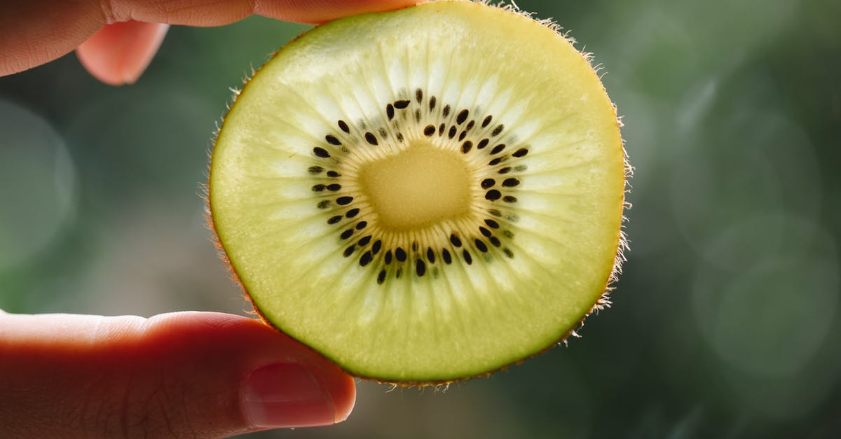Can seed show up in a place where similar seed already show up? - Crop anonymous person demonstrating pulp texture of ripe kiwi with seeds at sunshine