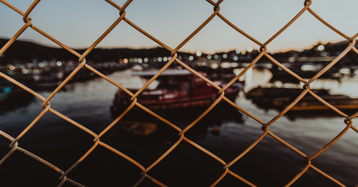Can ship upgrades be linked? - Through metal mesh fence of city port against evening sky