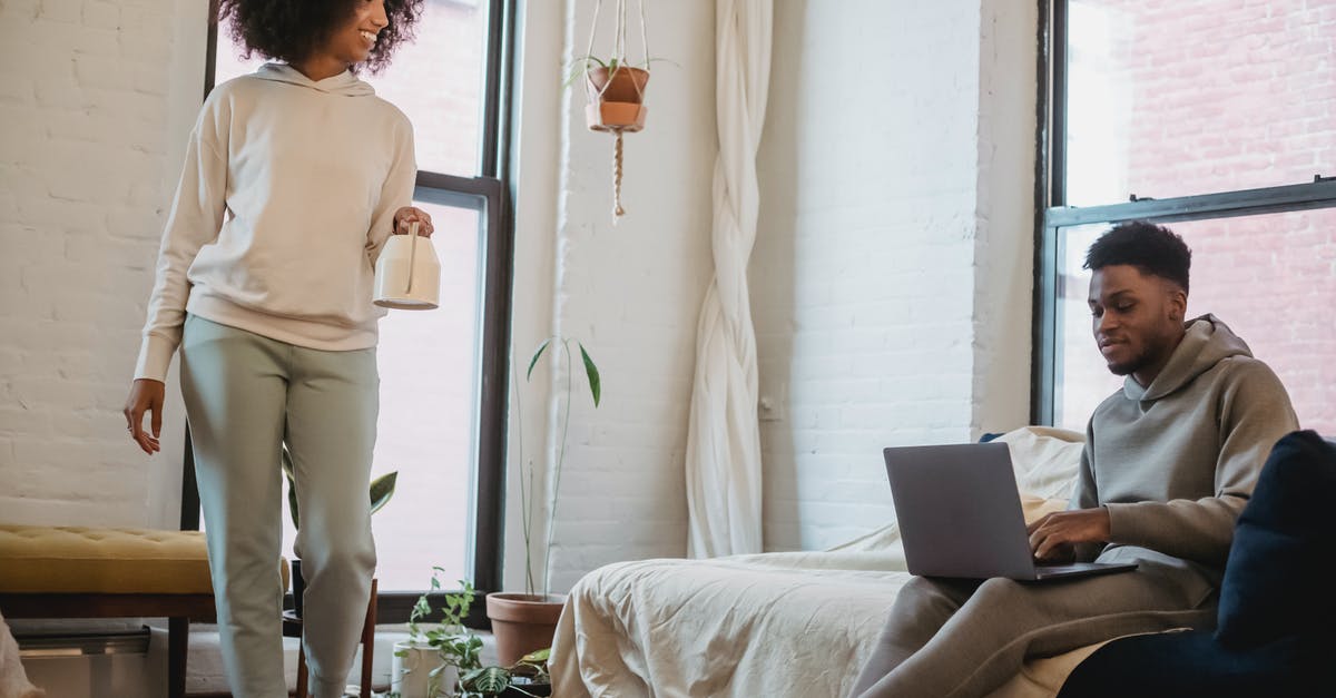 Can Spiritomb be encountered without a Nintendo Online account? - Happy young black woman with Afro hair in casual outfit smiling and walking in living room with watering can in hand near boyfriend working remotely on laptop