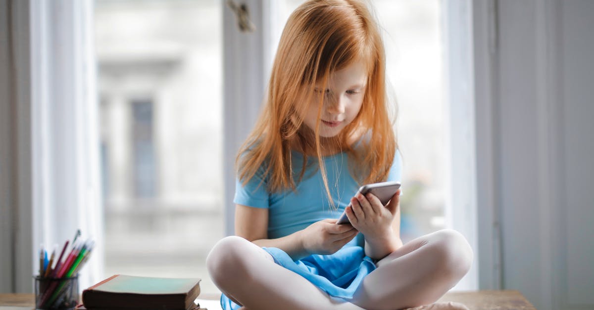 Can xbox360 and mobile cross play Minecraft [duplicate] - Red haired charming schoolgirl in blue dress browsing smartphone while sitting on rustic wooden table with legs crossed beside books against big window at home