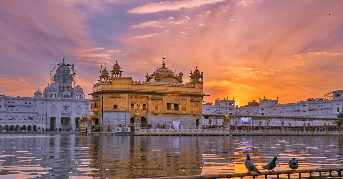 Can you enter the Imperial City, and towns and places like Cloud Ruler Temple? - Exterior of Sikh gurdwara golden temple with dome located near water against cloudy sky in evening time in city in India