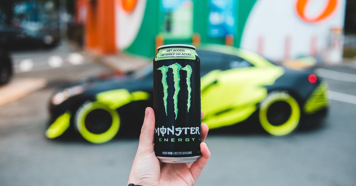 Can you increase your energy above maximum? - Unrecognizable person holding can of power drink while standing on parking lot near sport car