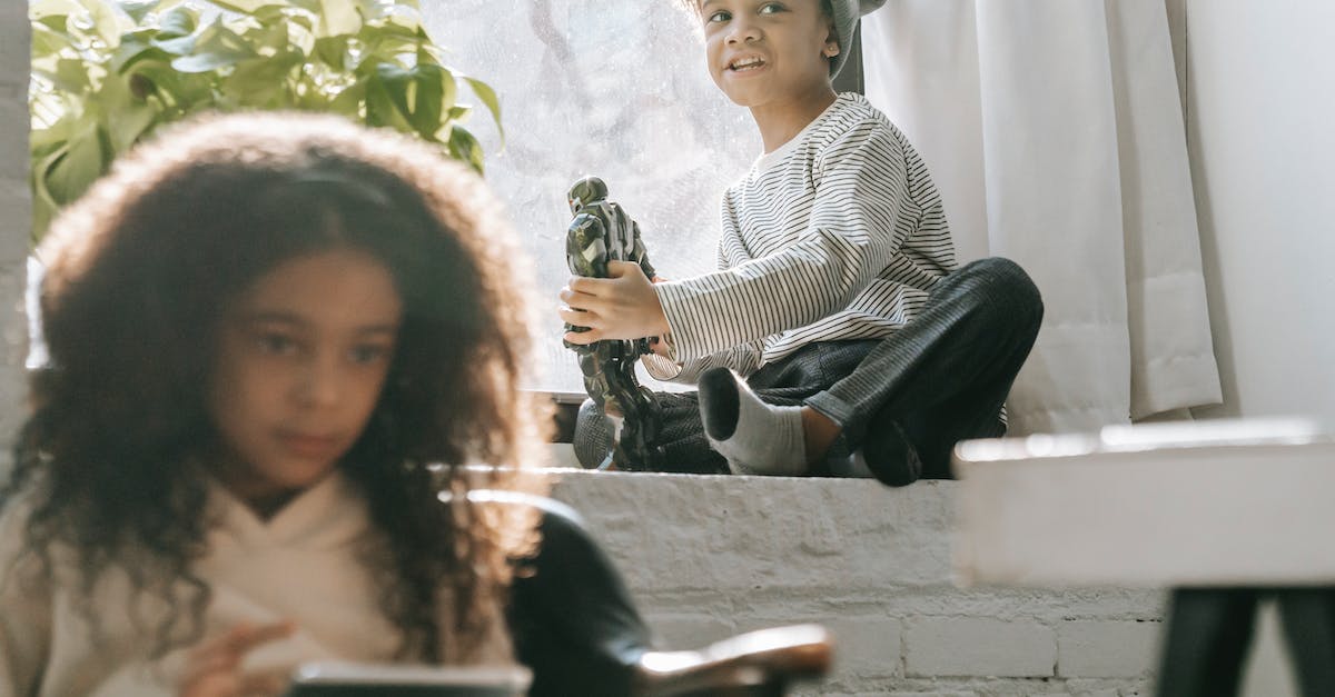 Can you play online with friends and strangers? - Black boy with robot toy near sister with tablet
