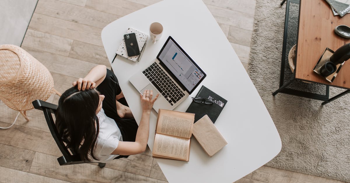 Can you rearrange items without using touch? - From above of young woman with long dark hair in casual clothes working at table and browsing netbook while sitting in modern workplace and touching hair