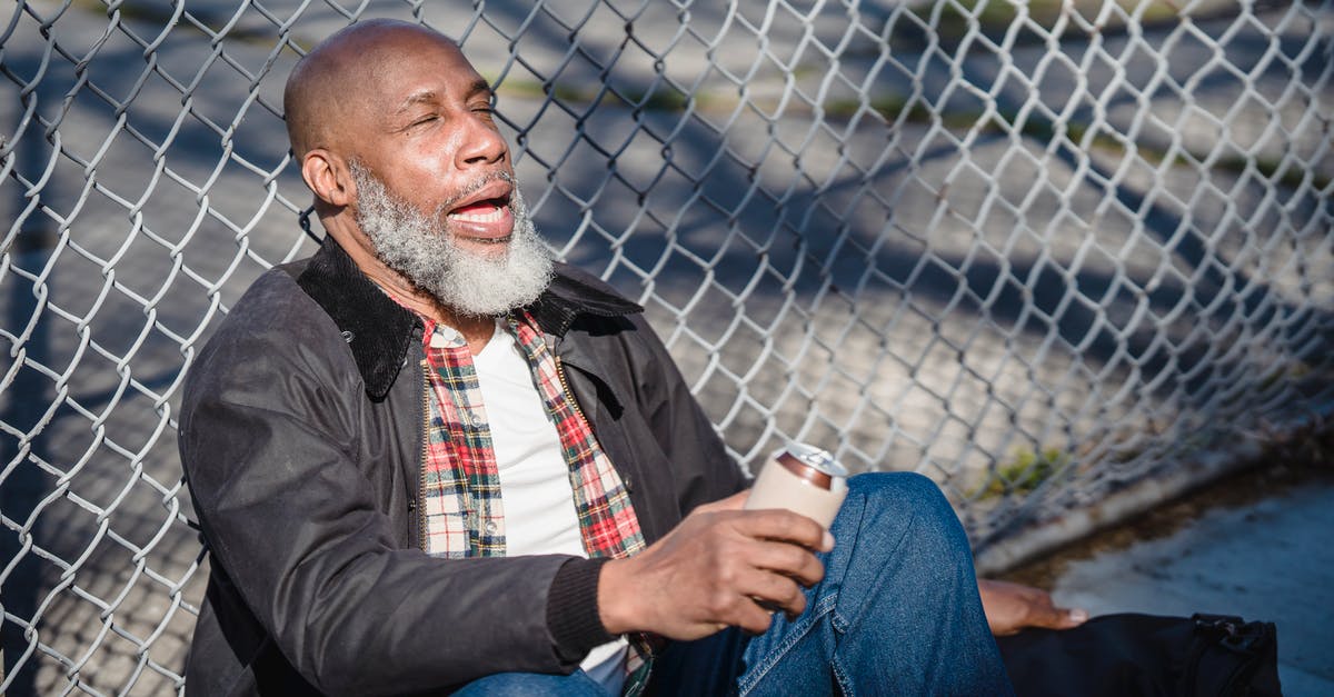 Can you use sleep dart on Junkrat's RIP-Tire? - African American senior man with closed eyes and opened mouth sitting near metal fence and holding beer can