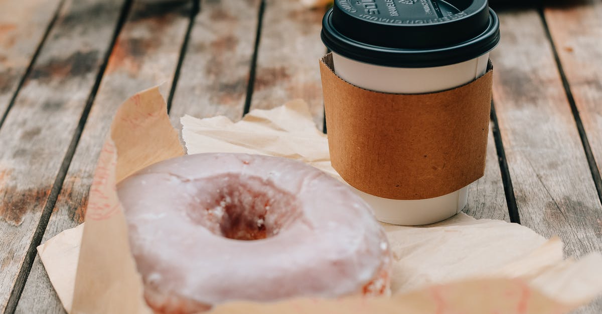 Candy on Let's Go Pikachu/Eevee - Tasty sweet chocolate donut and takeaway cup of coffee placed on wooden surface in daytime