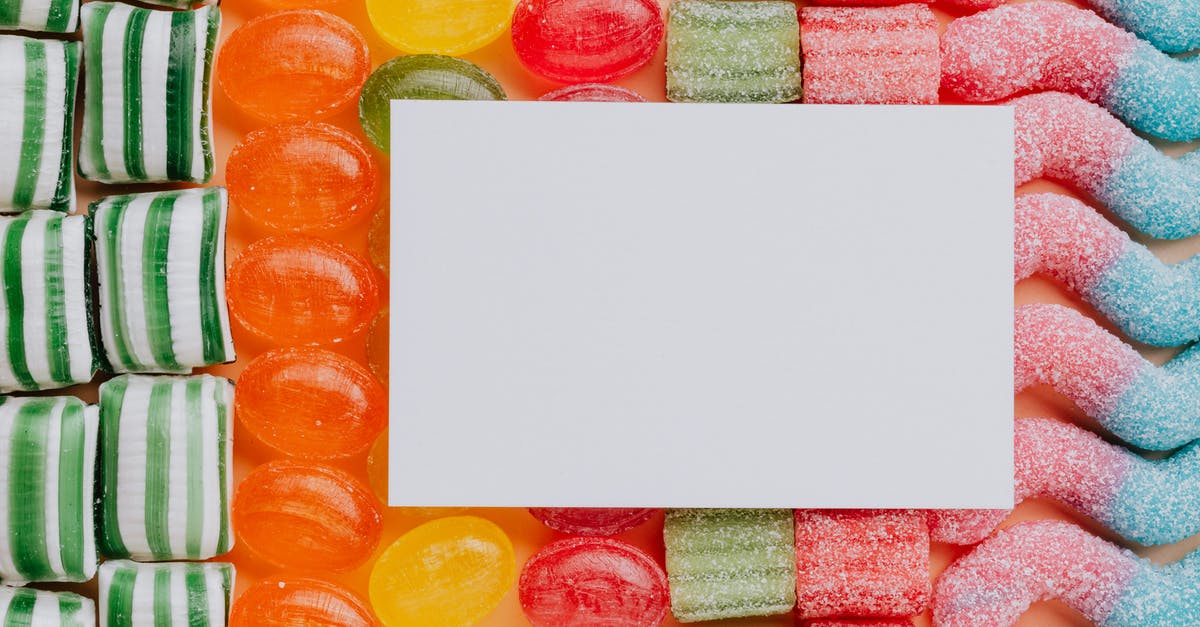 Cannot complete card collection contracts - Top view closeup of blank paper card placed on multicolored various shapes yummy candies in light confectionery
