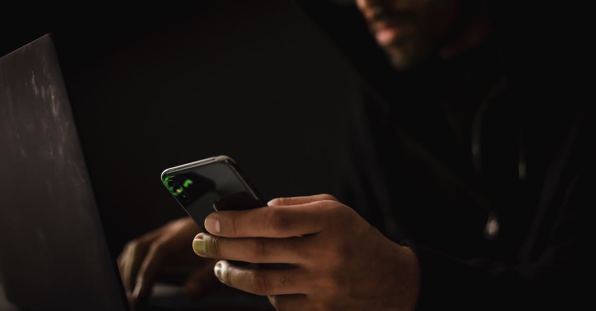 Cannot Hack Maurice phone with the PC - Crop anonymous ethnic male cyber spy with cellphone and netbook hacking system in evening