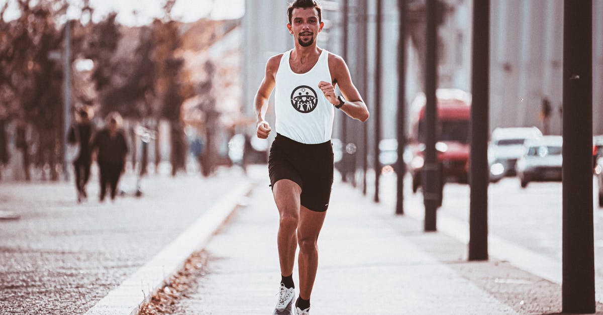 Challenge room locked at full health - Full body of runner in sportswear jogging along paved pavement in sunny day in city Challenge room locked at full health - Full body of runner in sportswear jogging along paved pavement in sunny day in city
