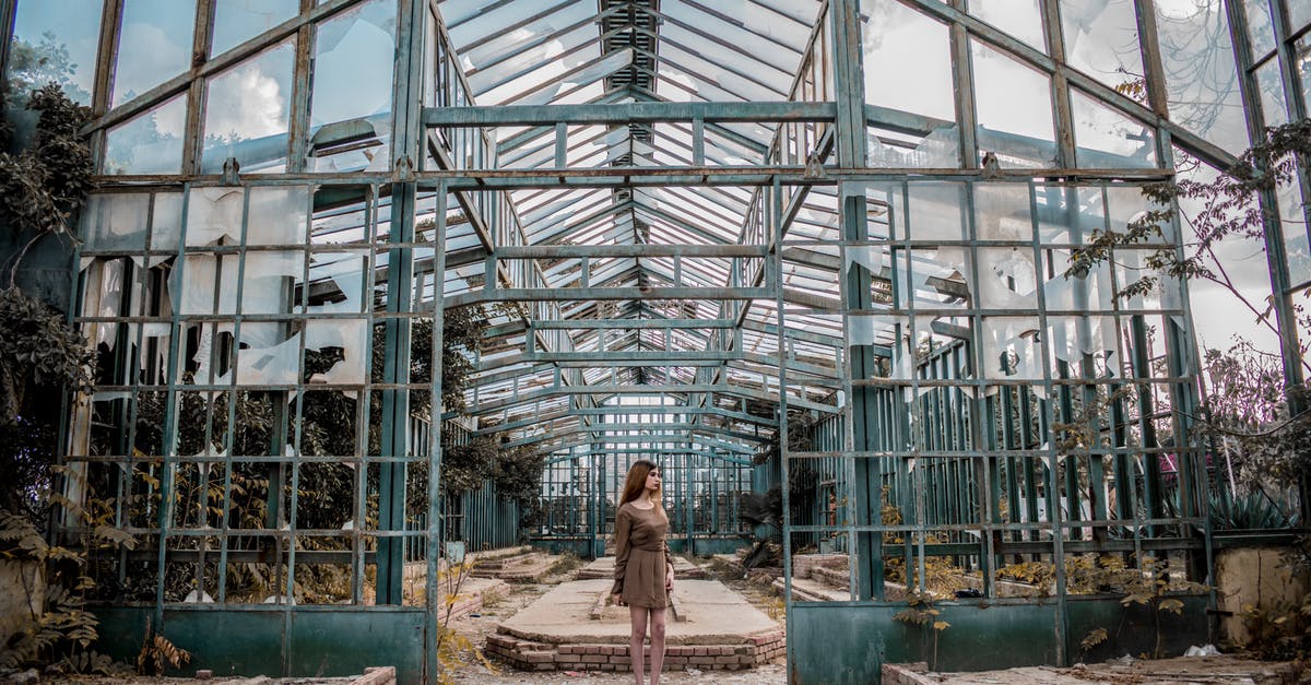 Change email on old account - Full body of slim anonymous lady looking away while standing on dry terrain near big half destroyed symmetric construction with brick platforms under sky with clouds in daylight