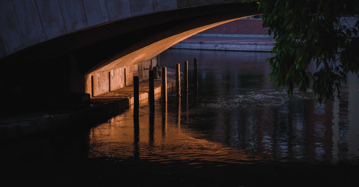 Channelling/digging under a bridge - Narrow space and enclosure under concrete bridge over calm rippling river in dusk