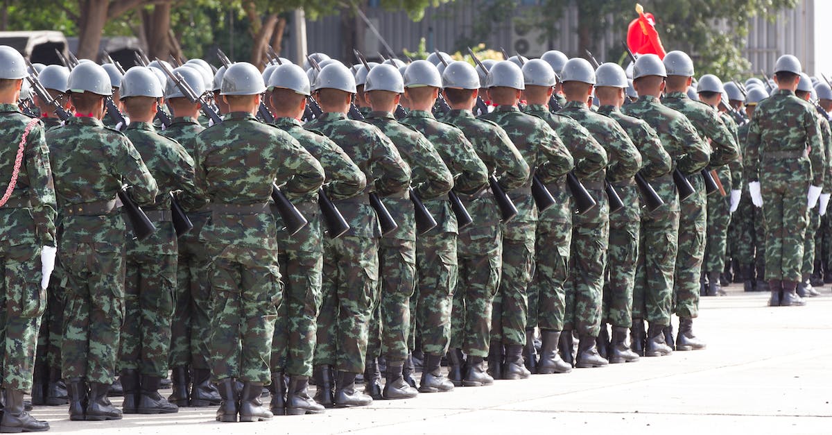Character gains military traits despite not leading troops - Back view unrecognizable soldiers with riffles wearing khaki uniform and hardhat lining up in rows during military ceremony Character gains military traits despite not leading troops - Back view unrecognizable soldiers with riffles wearing khaki uniform and hardhat lining up in rows during military ceremony