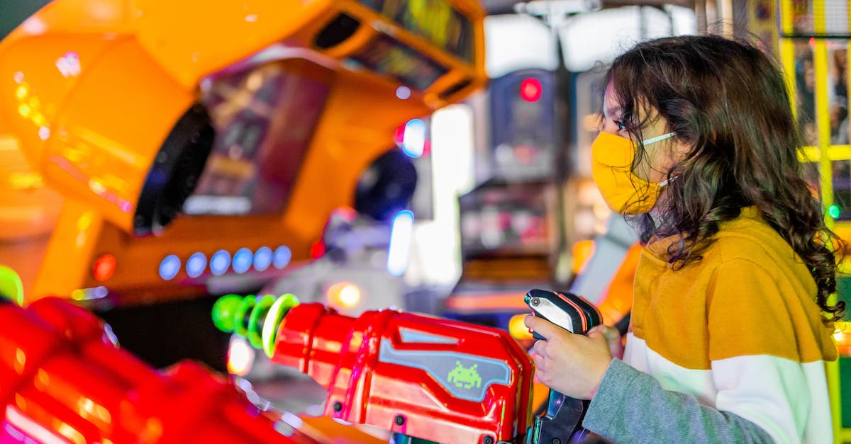 Charged shots shooting wrong way with controller - Side view of focused child in face mask playing shooting gaming machine with joysticks in arcade Charged shots shooting wrong way with controller - Side view of focused child in face mask playing shooting gaming machine with joysticks in arcade