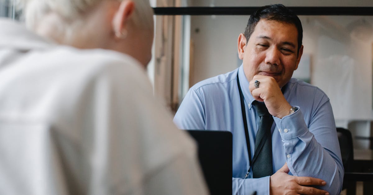 Cheating expert bosses - Confident ethnic male employee sitting at contemporary workplace and looking satisfied while young male client sitting in front